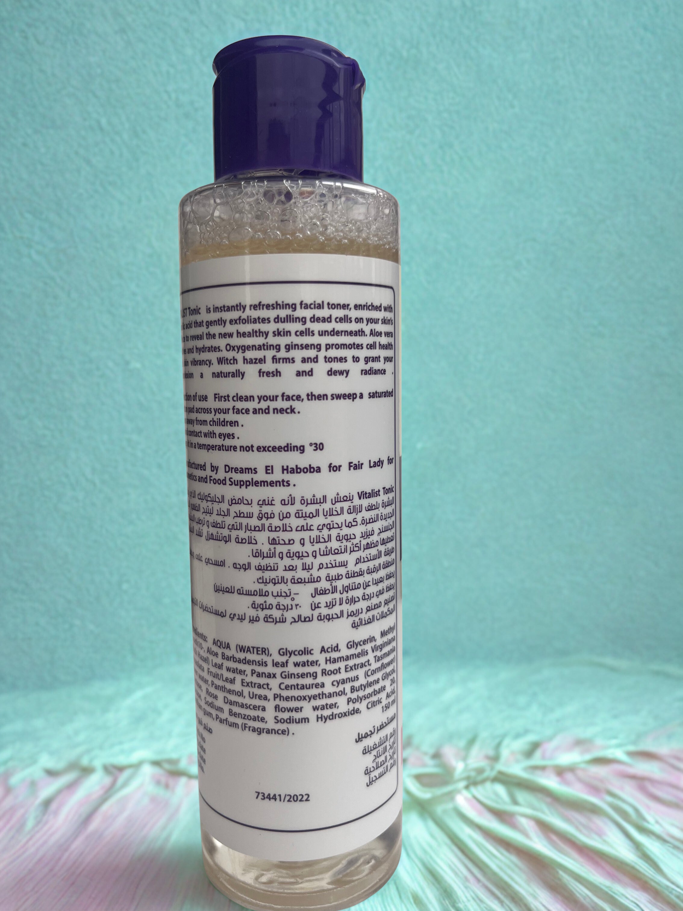 Bottle of facial toner with a purple cap on a light blue background label